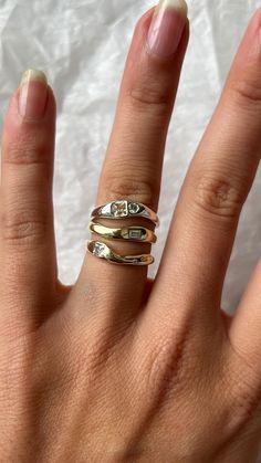 a woman's hand with three different rings on her fingers and one ring in the middle