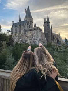 two people standing in front of hogwarts castle looking at the sky with their arms around each other