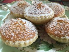 four powdered sugar cookies sitting on top of a green and white plate with gold trim