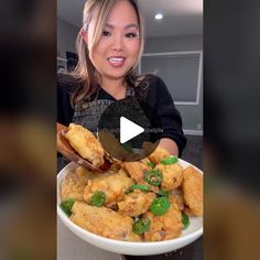 a woman holding a spoon full of fried food in a white bowl with green peppers