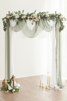 a wedding arch decorated with flowers and greenery on the floor in front of a window