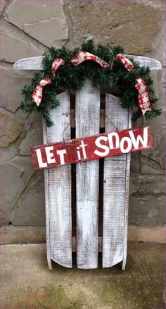 a sign that says let it snow on top of a sled with wreaths