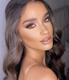 a woman with long hair and brown eyes is posing for the camera, she has her hand on her shoulder