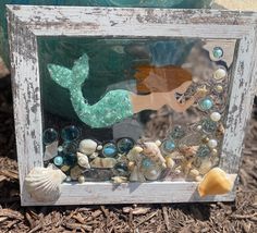 an old frame is decorated with sea shells and mermaid silhouettes