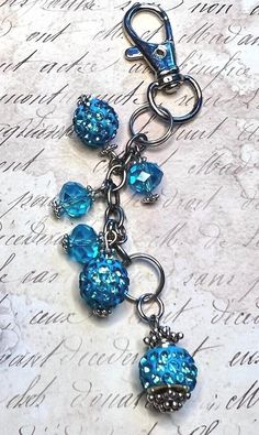 a key chain with blue beads hanging from it's end on top of a piece of paper