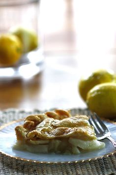 a piece of pie sitting on top of a plate next to lemons and a fork