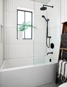 a white bathroom with black and white decor on the shower wall, bathtub, and towel rack