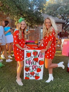 two women in red dresses holding a sign that says love and cherry moo