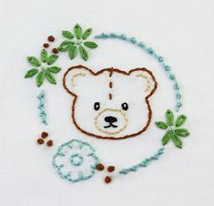 a white teddy bear with green leaves on it's head and some beads around its neck