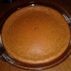 a cake sitting on top of a wooden table next to a glass bowl filled with batter