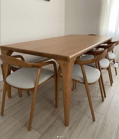 a wooden table with six chairs around it in a room that has white walls and wood floors