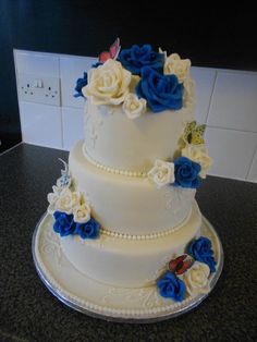 a three tiered cake with blue and white flowers on the top is sitting on a counter