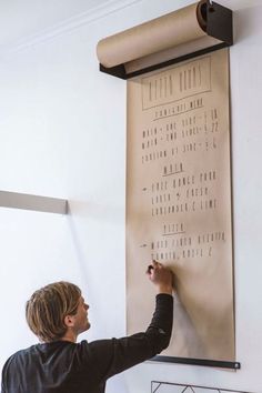 a man writing on a wall with a roll of paper