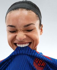 a woman smiling and holding up a blue jacket