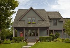 a red house with gray shingles and black shutters on the front door is shown