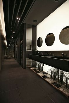 a bathroom with black counter tops and round mirrors on the wall, along with potted plants