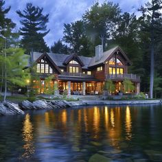 a large house sitting on top of a lake next to a forest