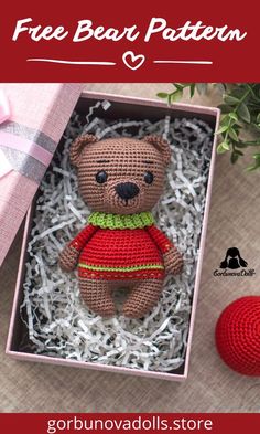 a crocheted teddy bear in a box next to a red ball and green plant