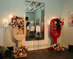 a room with flowers and decorations on the wall, in front of a large mirror