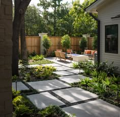 an outdoor patio with seating and trees in the back yard, surrounded by greenery