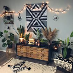 a room filled with lots of plants and lights hanging on the wall above it's dresser