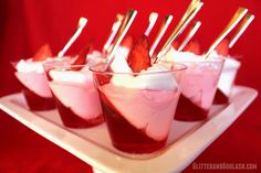 small desserts with strawberries and whipped cream on a white platter against a red background