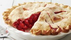 a pie with a slice missing from it sitting on a white plate next to utensils