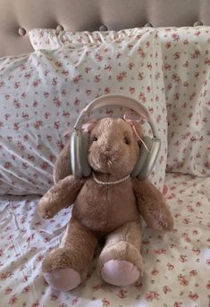 a teddy bear with headphones sitting on a bed