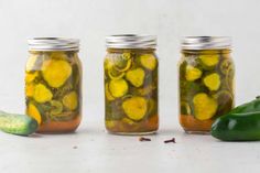 three jars filled with pickles and cucumbers