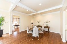 a dining room with hard wood flooring and white walls in the middle of it