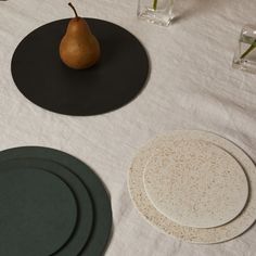 three plates and a pear on a table