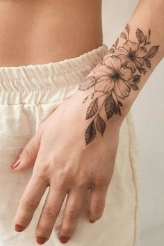 a woman's hand with a flower tattoo on it