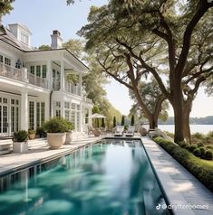 a large house with a pool in front of it and lots of trees on the other side