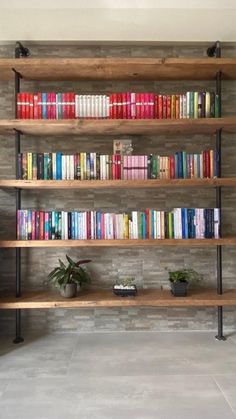 a bookshelf filled with lots of books next to a plant on top of a tiled floor