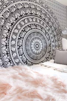 a large black and white tapestry hanging on the side of a wall next to a bed