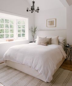 a white bed sitting under a window in a bedroom