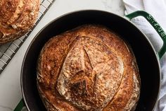 two loaves of bread sitting in a pan on top of a counter next to a cooling rack