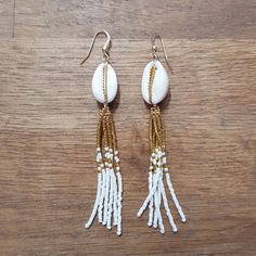 white and gold beaded earrings with tassels on wooden surface, close up