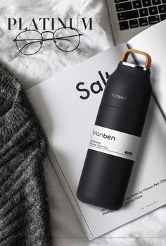 a black bottle sitting on top of a book next to a pair of eyeglasses