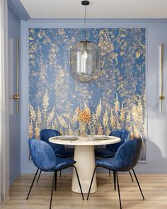 a dining room with blue chairs and a white table in front of a floral wallpaper