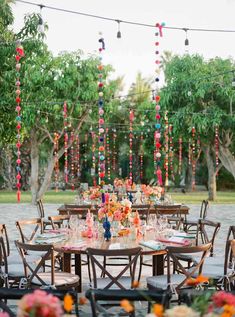 an outdoor table set up for a party with lots of colorful beads hanging from the ceiling