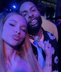 a man and woman are posing for a photo in front of a crowd at a party