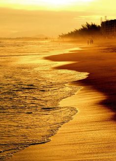 the sun is setting at the beach with waves coming in