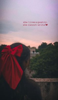 a woman with a red bow on her head looking out over the city at sunset