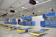 an industrial garage with blue tool cabinets and yellow flooring on the floor, overhead lighting above