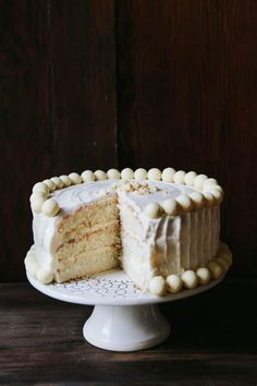 a cake with white frosting and small pieces taken out of it on a plate