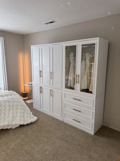 a bedroom with white furniture and carpeted flooring