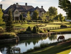 two horses graze in front of a large house on the water's edge