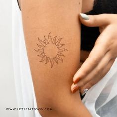 a woman's arm with a small sun tattoo on the left side of her body