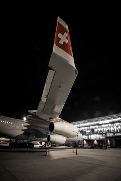 an airplane is parked in front of a large building with lights on it's sides